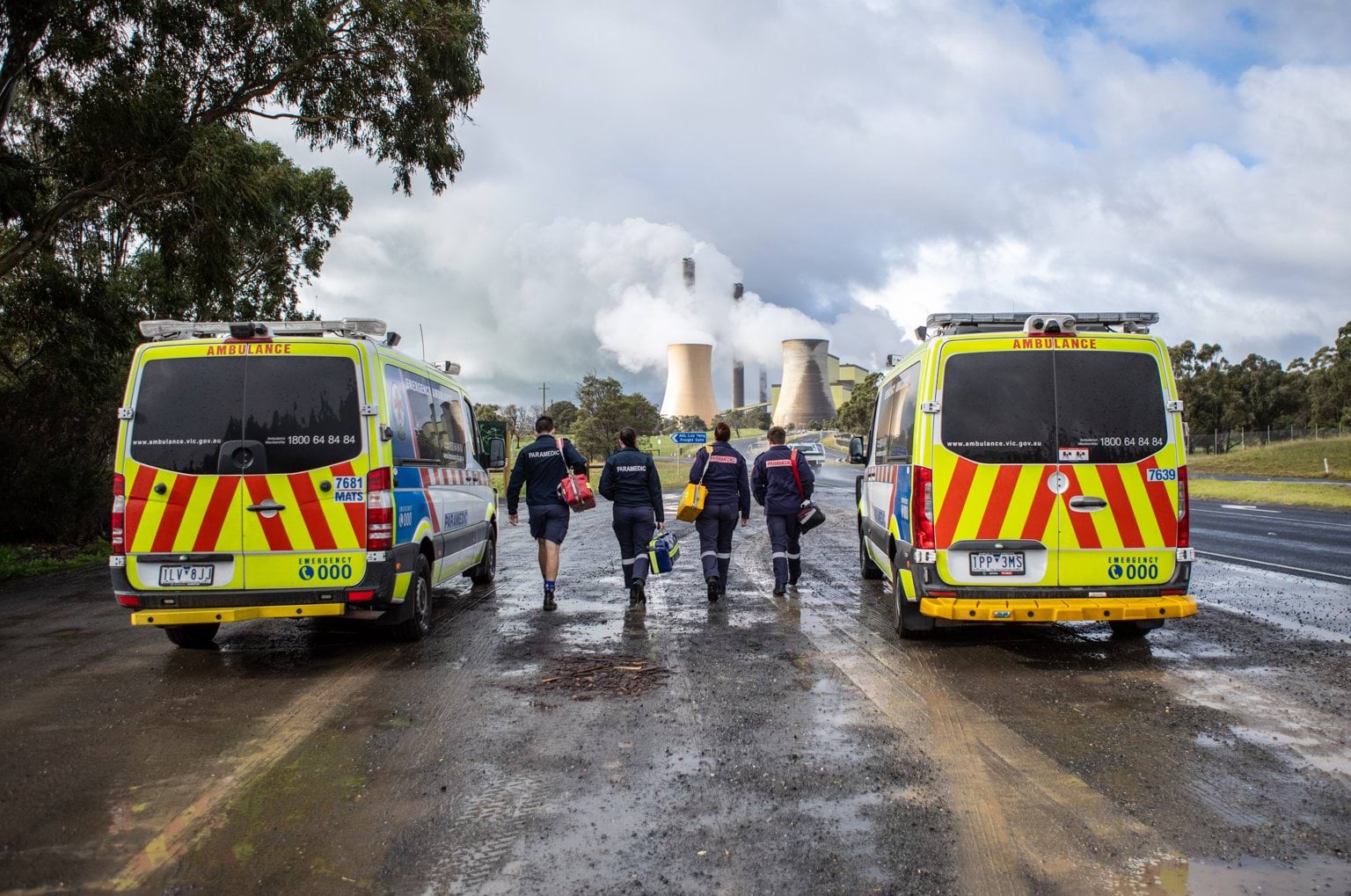Four paramedics walking between two ambulances