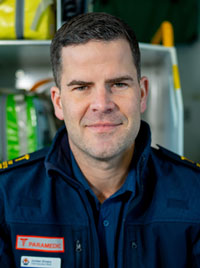 A man in paramedic uniform poses for a corporate photo