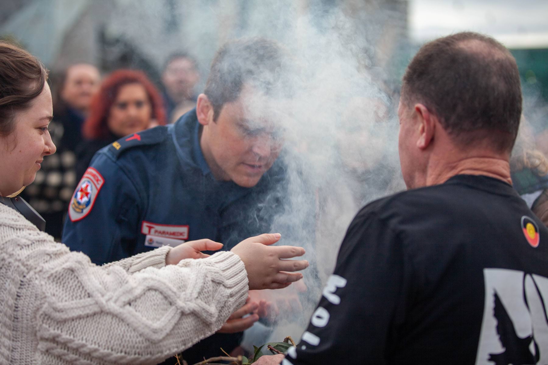 A man in paramedic uniform takes part in a smoking ceremony.