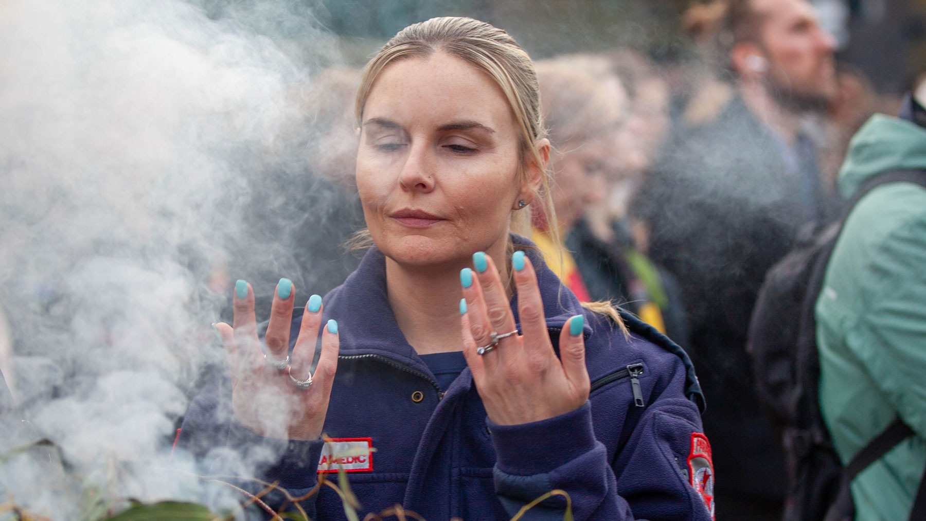 A woman in a paramedic uniform takes part in a smoking ceremony.