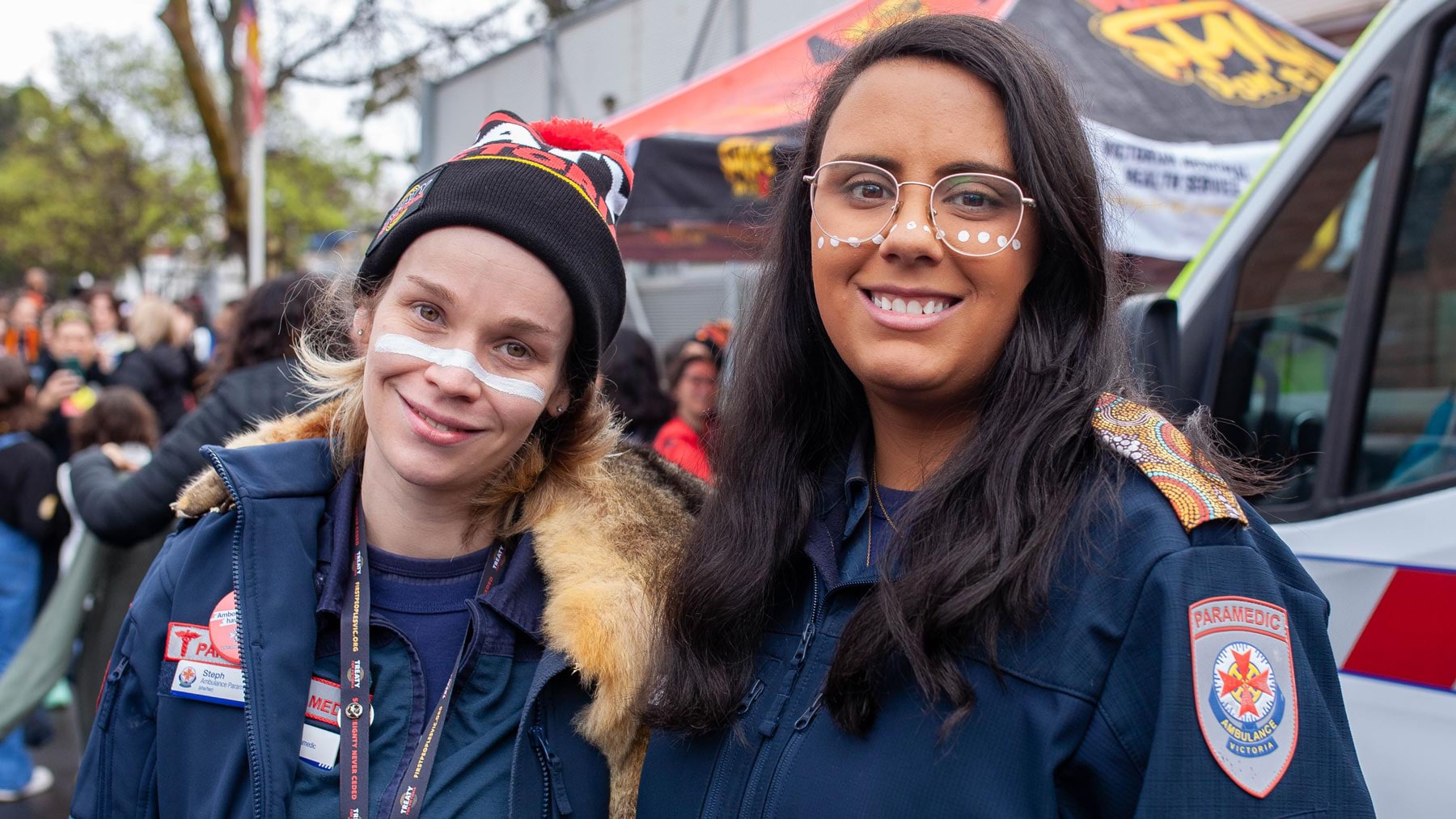 Two paramedics stand together in front of an ambulance