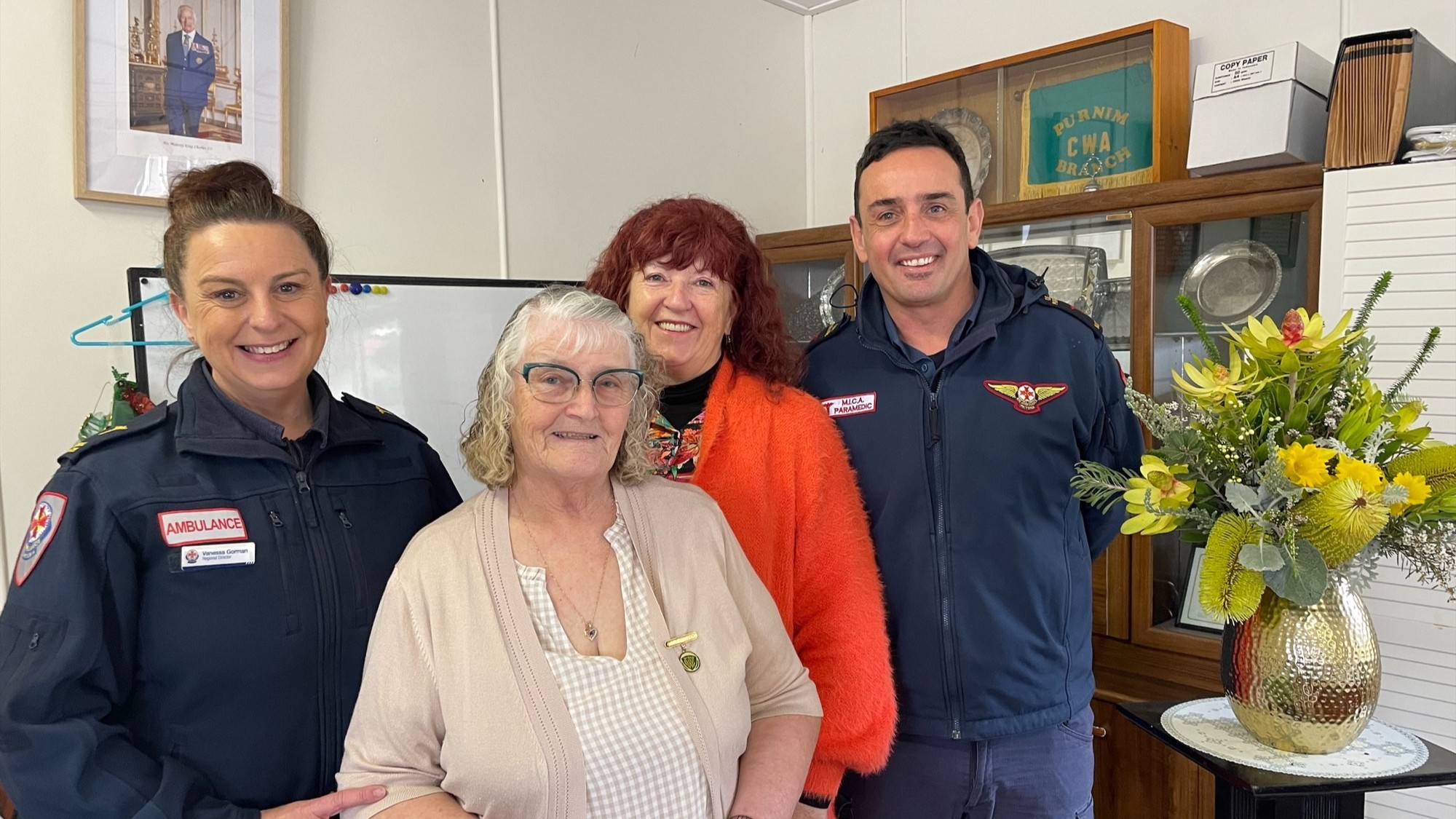 Two smiling women standing in between two smiling paramedics.