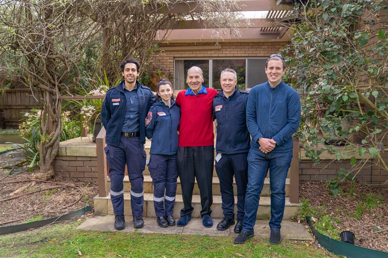 A patient is standing with the paramedics and responders who saved his life