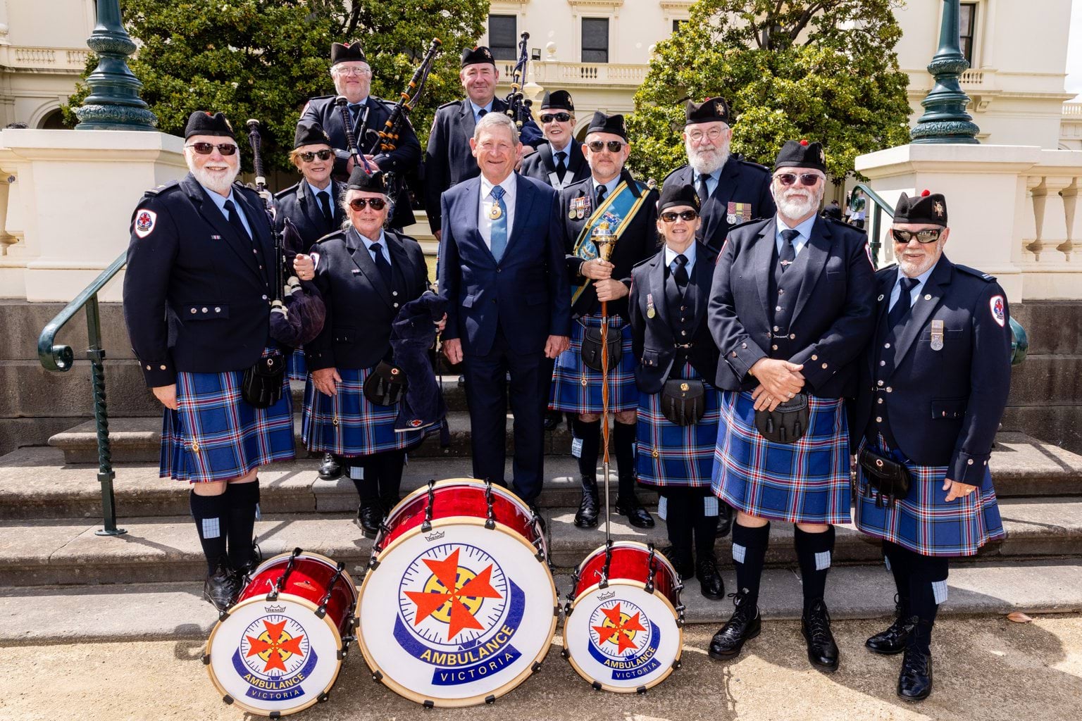 Members of AV Pipes and Drums pose outside in uniform