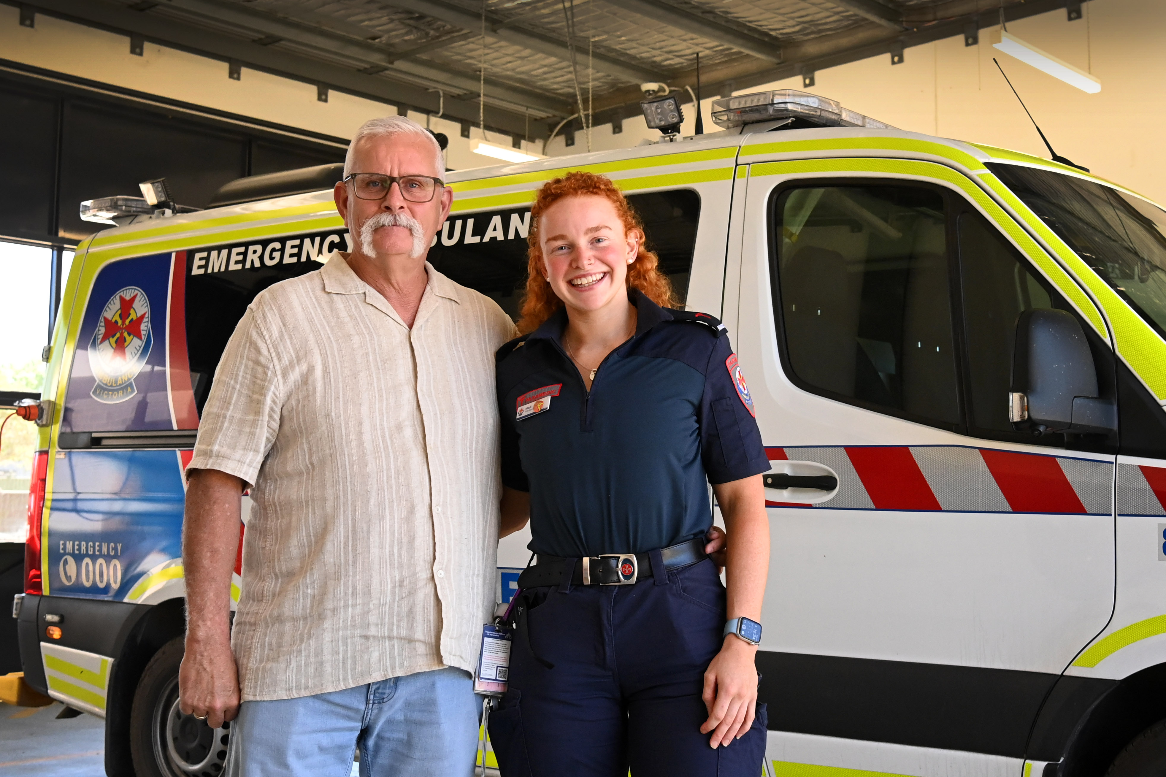 A man in casual clothes and a paramedic smile with an arm around eachother.