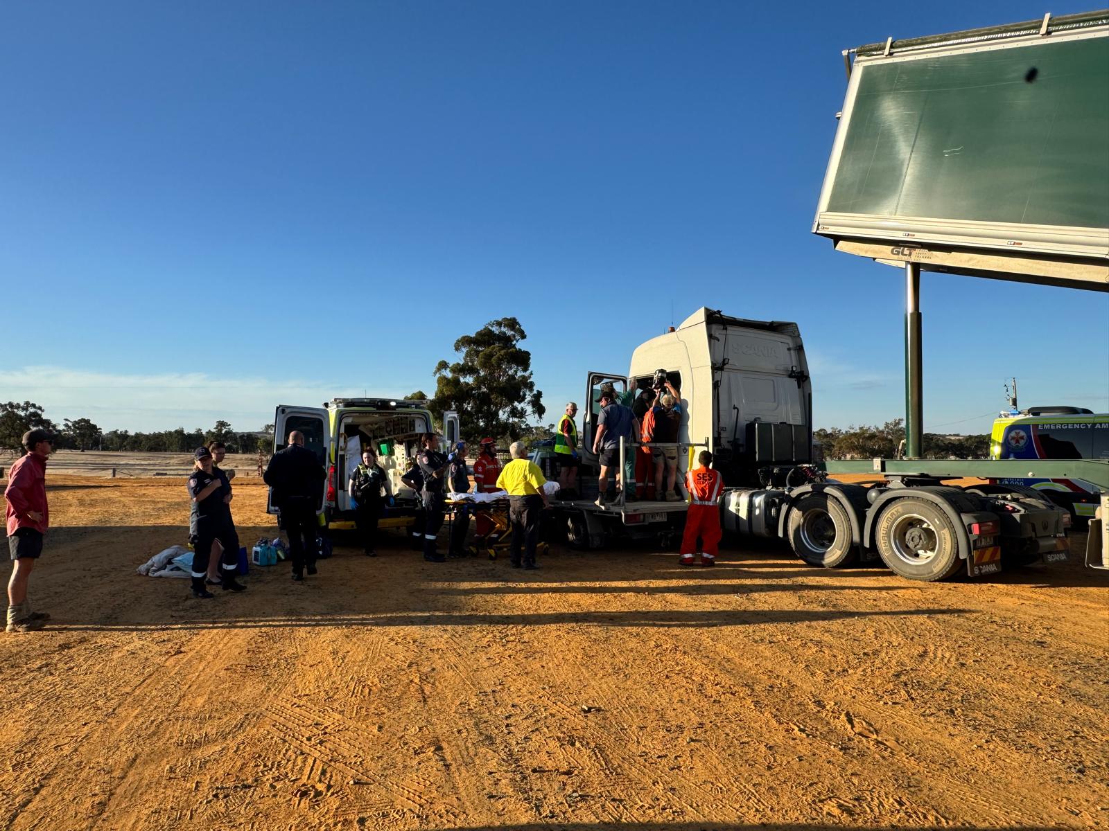 A group of first responders gather around and inside a truck on a farm.