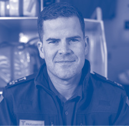 A man in paramedic uniform looks directly at the camera